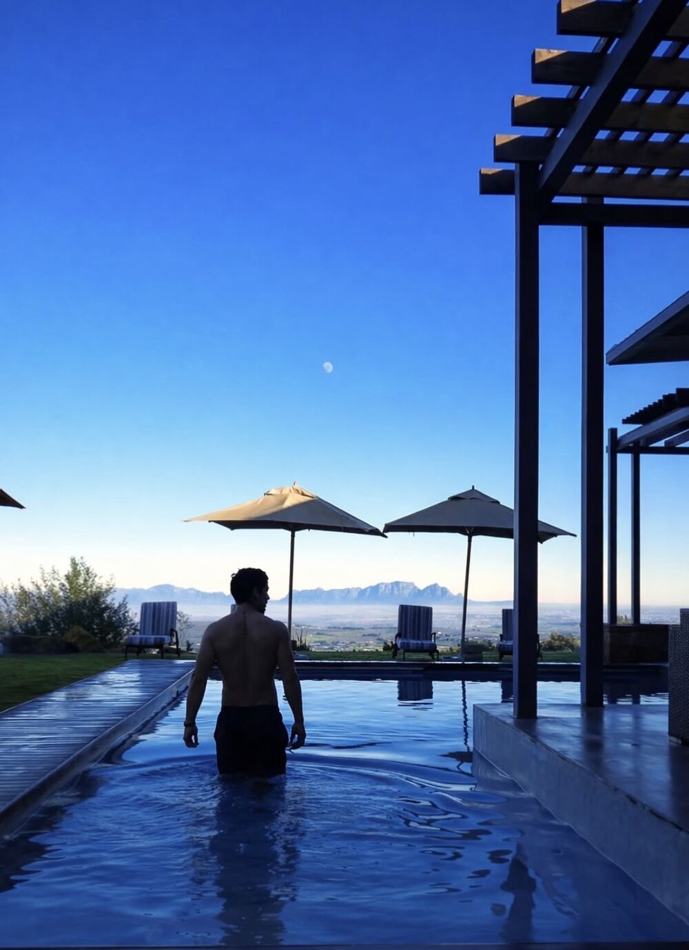 Infinity pool at dusk with the moon over the Helderberg